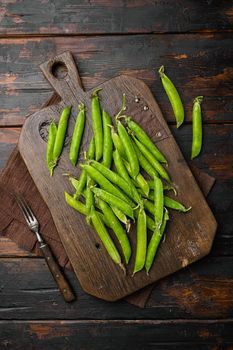 Fresh picked green pea on old dark wooden table background, top view flat lay
