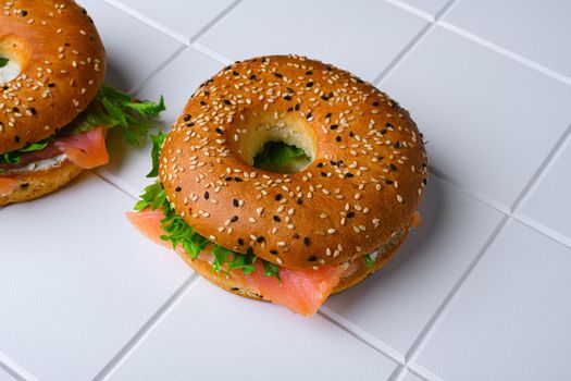 Cream cheese and smoked salmon bagel, on white ceramic squared tile table background, with copy space for text