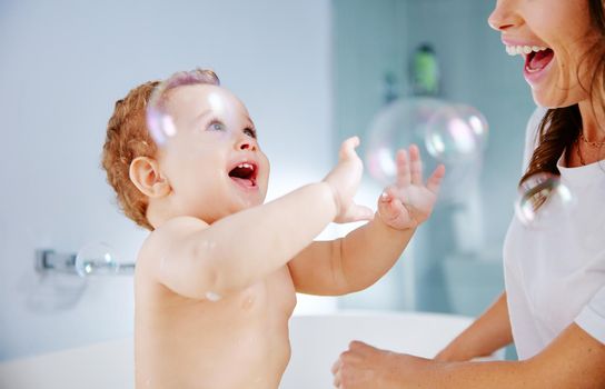 Bubbles are always fun. Shot of a mother bathing her baby at home.