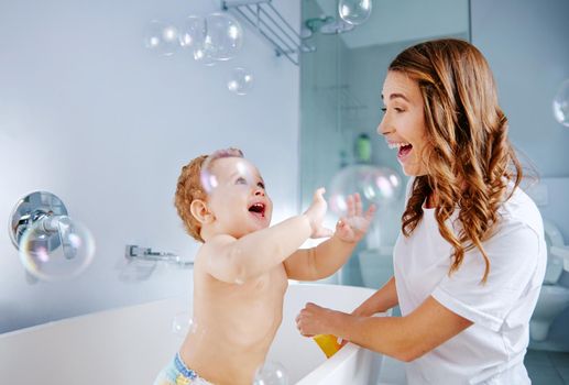Bubbles make bath time more fun. Shot of a mother bathing her baby at home.
