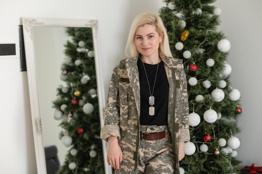A female soldier, military woman standing in front Christmas tree