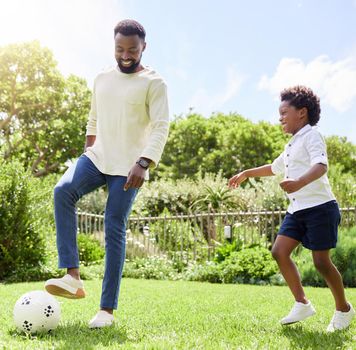 Who will score the first goal. Shot of a father and son playing soccer together outdoors.