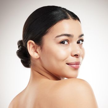 Face of a young beautiful mixed race woman smiling and posing against a grey studio background. Confident hispanic female posing against a background