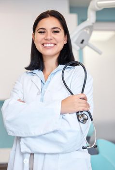 Confident young female dentist working in a medical office. One caucasian woman standing with her arms crossed while holding a stethoscope. Oral hygienist ready for checkup to maintain dental health