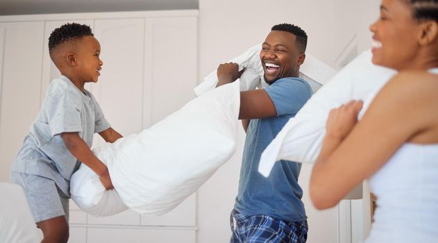 Who will be crowned as the pillow fight champion. Shot of a happy family having a pillow fight together at home.