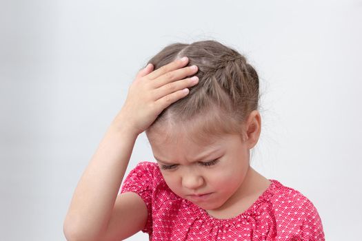 Child with headache holding hand on head