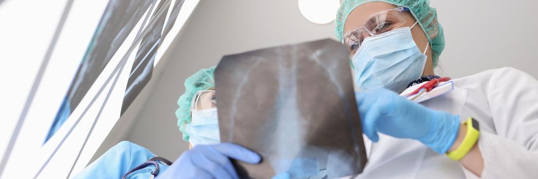Medical workers examine x ray of patient lungs, colleagues discuss scan result