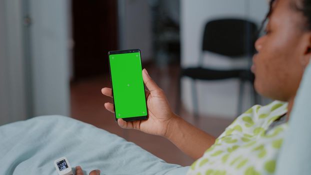 Close up of patient holding smartphone with green screen