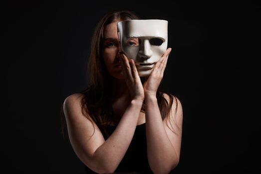Its the only way Ill fit in. Studio shot of a woman hiding behind a blank mask.