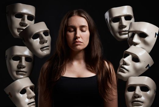 Im in control of my own emotions. Studio shot of a woman standing with her eyes closed while surrounded by masks.