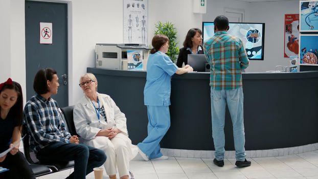 Diverse group of patients sitting in waiting room area to register for appointment