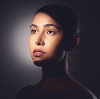 A major component of healthy skin is a natural glow. Studio shot of a beautiful young woman posing with light beam against her face.