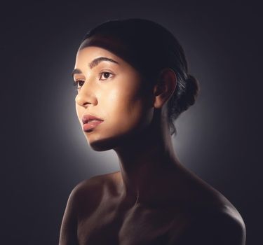 Its important to make a conscious effort to look after your skin. Studio shot of a beautiful young woman posing with light beam against her face.