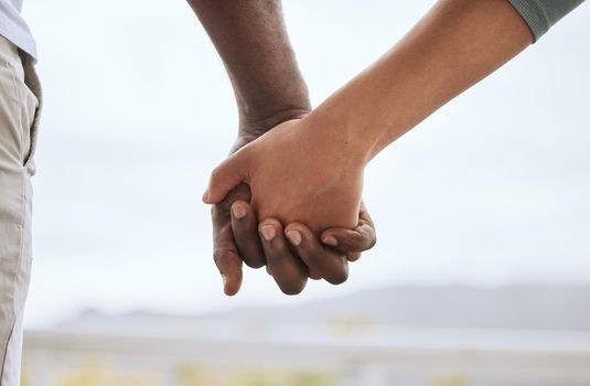 Closeup of biracial couple interlocking fingers and holding hands while bonding outdoors. Caring mixed race woman united with african american man. Together in support and a loving relationship