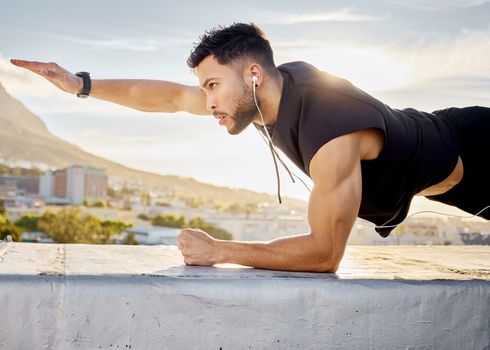 Just keep pushing forward. Shot of a man doing a single-arm plank while on a rooftop.