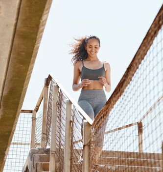A workout for the heart. Shot of an attractive young woman running down stairs during her outdoor workout in the city.