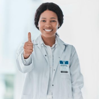 Some heroes wear white coats. Portrait of a young doctor showing thumbs up in a hospital.