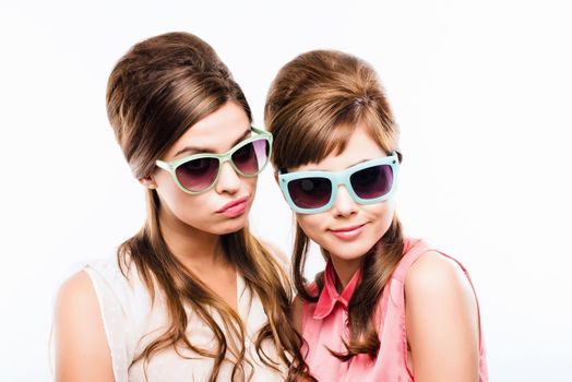 Keeping the sixties alive. Studio shot of two attractive young women dressed up in 60s wear against a white background.