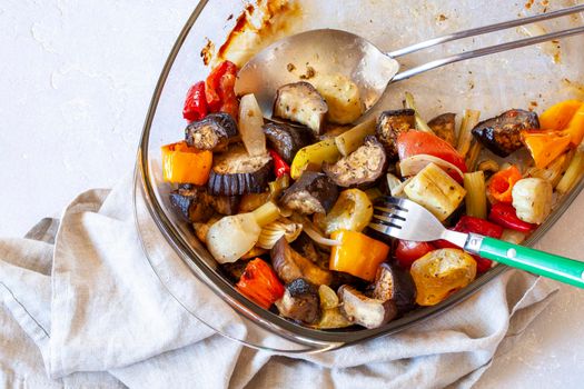 Oven dish with baked vegetables and cutlery