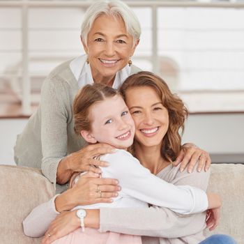 Portrait of a grandmother relaxing with her daughter and mother. Little girl bonding with her parent and grandparent in the living room at home. Three generations spending time together