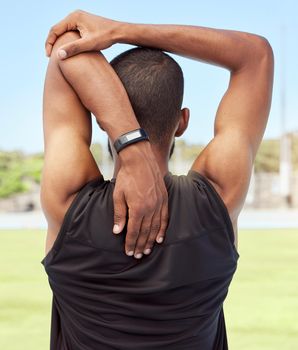 Athletic man preparing for fitness and exercise by stretching and warming up outside on a sports field. Male athlete going through his warmup routine before exercise or a cardio or endurance workout