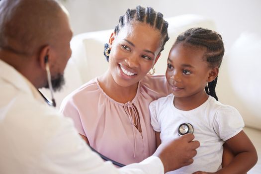 African american male paediatrician examining sick girl with stethoscope during visit with mom. Doctor checking heart lungs during checkup in hospital. Smiling daughter receiving medical care