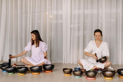 Two female yoga teachers play on Tibetan bowls in the gym during a yoga retreat