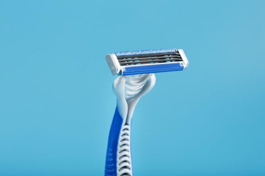 Razor blades on a blue background with drops of icy water