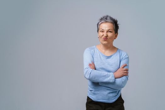 Showing positive dislike on her face mature business woman with grey hair in 50s with hands folded and copy space on left for product placement isolated on white background