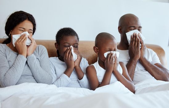 Flu season. Shot of a family blowing their noses while sick at home.