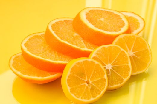 Orange and lemon slices on the yellow background - stock photo