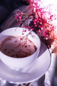 White cup of milk and chocolate. Morning aesthetics vibes. Breakfast. Pink gypsophila flowers