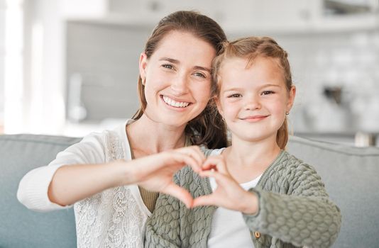 Daughters are born into your heart. Shot of a mother and daughter making a heart sign with their hands at home.