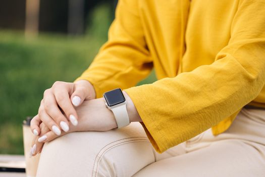 Smart watch on woman's hand outdoor. Woman's hand touching a smartwatch. Female's hand uses of wearable smart watch at outdoor