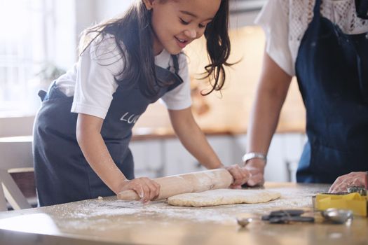 Baking sure is fun. Shot of an adorable little girl rolling out dough.