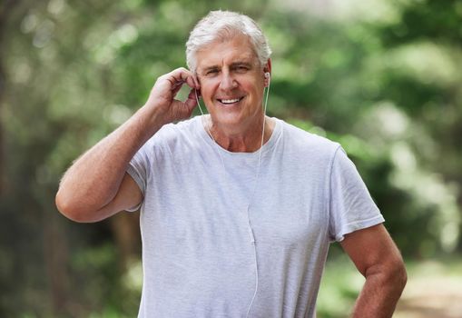 Keeping active keeps me healthy. Portrait of a mature man wearing wireless earphones while exercising outdoors.