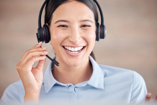 Smiling mixed race call centre agent wearing headset with microphone and talking to customers. Female customer service representative using headset and consulting clients online. Helpdesk and hotline