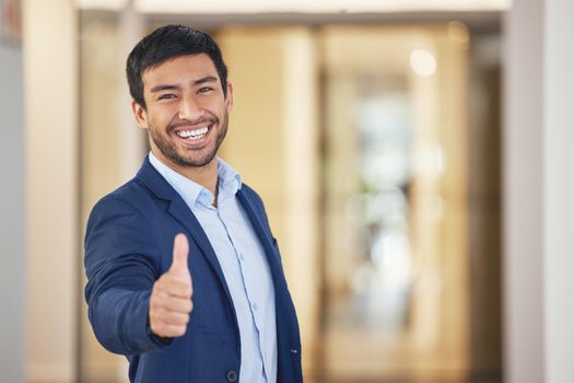 I want to see you succeed as well. Portrait of a young businessman showing thumbs up in an office.
