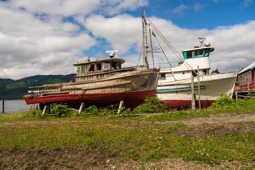 Historic but rotting fishing boats by ocean at Icy Strait Point
