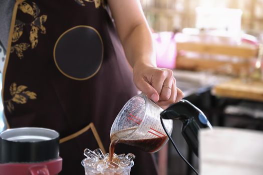 A female employee pours coffee into a plastic cup for customers