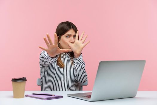 Emotional young woman sitting and working on office with pink background.
