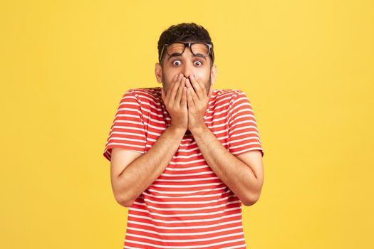 Emotional young man in red t-shirt on yellow background.