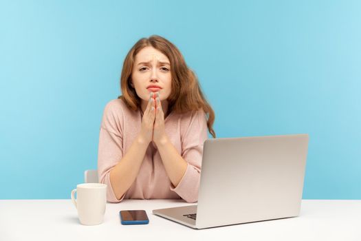 Emotional young woman working on laptop on blue background.