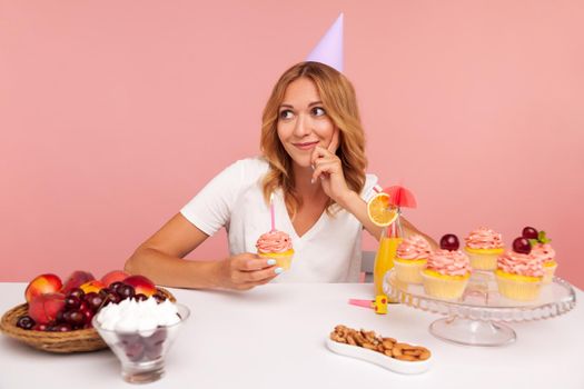 Indoor cooking of young woman on pink background.