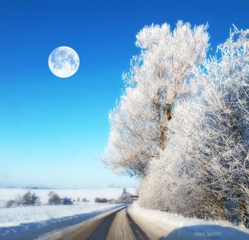 The moon in winter landscape. Road with ice on a winter landscape during noon. The Moon shines through clear clouds