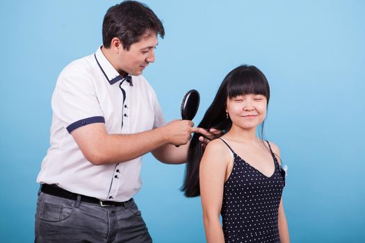 Caucasian boyfriend brushing his girlfriend hair in studio