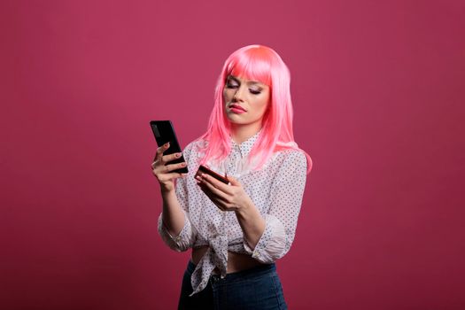 Female model with pink hair using credit or debit card