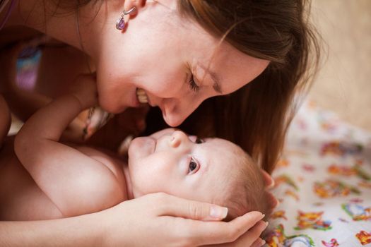 Close up portrait of beautiful young smiling mother kissing her baby