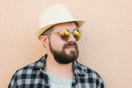 Bearded man portrait in summer clothes and hat stand over beige wall on street city urban and travel concept