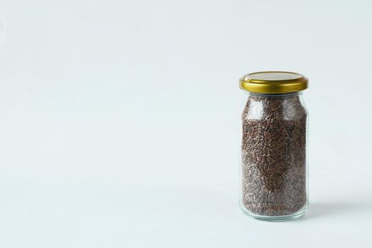 flax seeds in a glass jar on white background